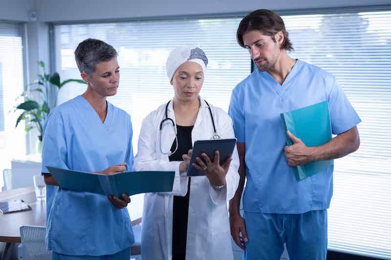 Three doctors standing around looking at a clip board